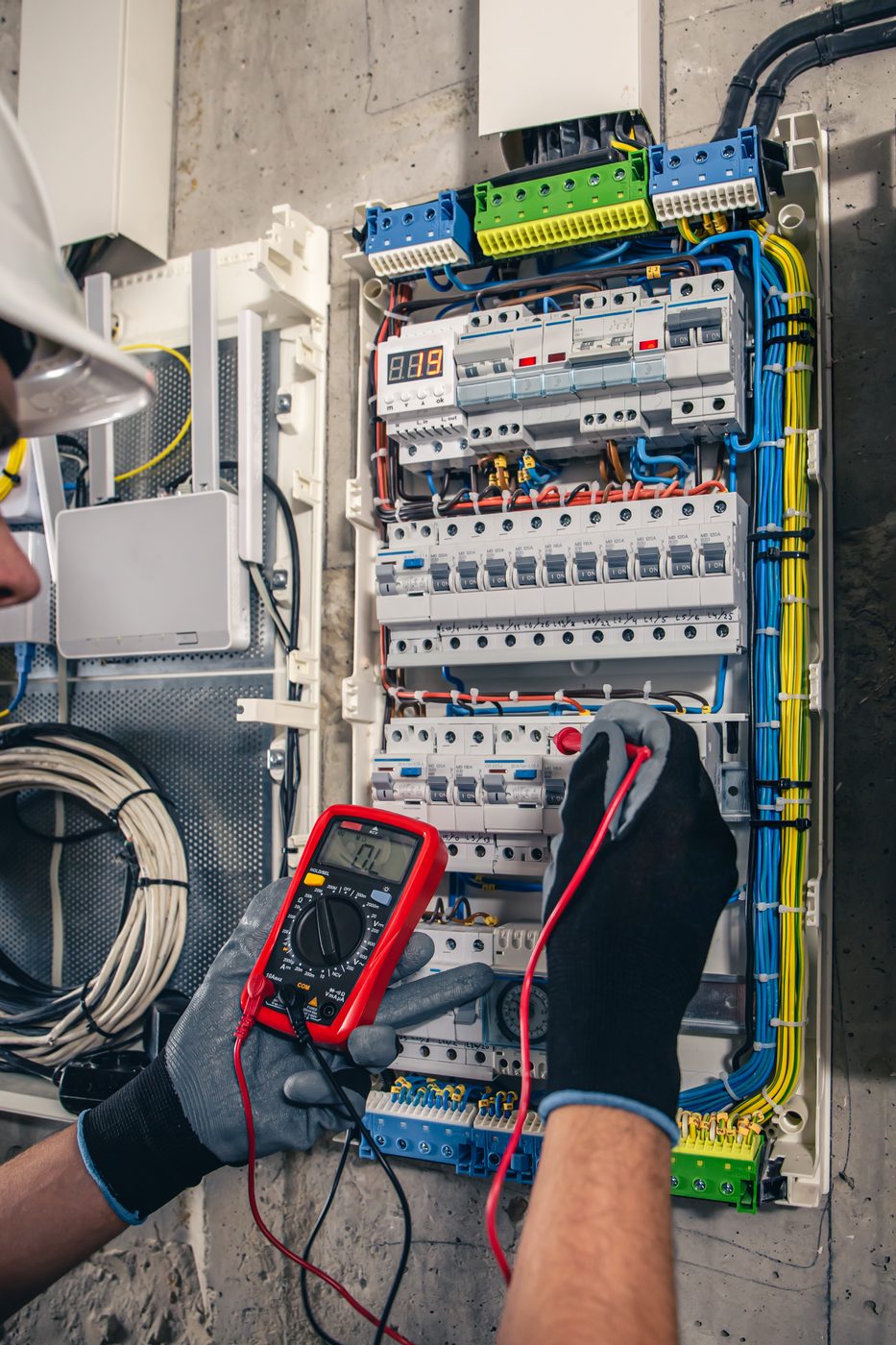 Elektriker misst Verteilung mit Multimeter, VDE-Prüfung